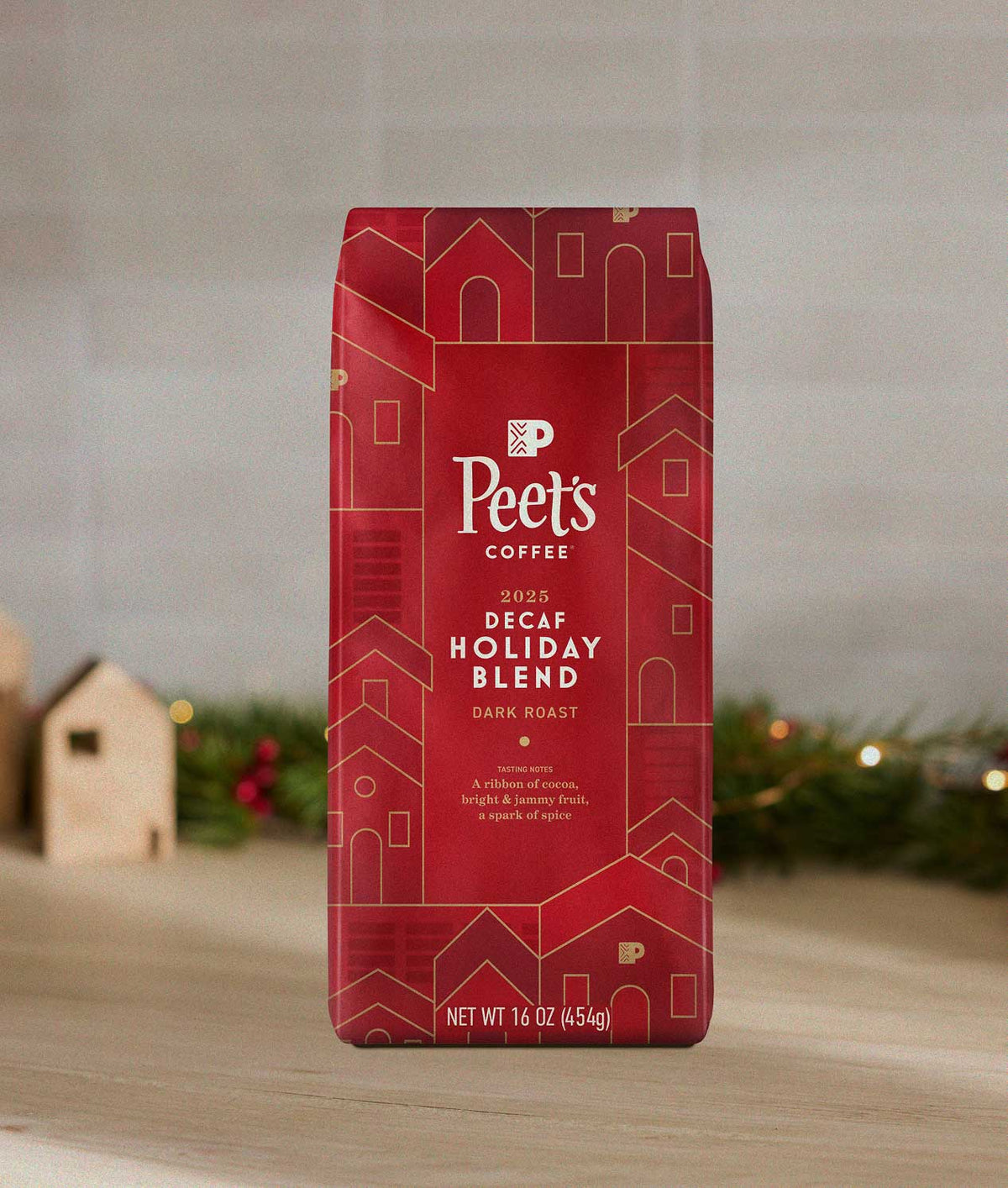 Red Peet's Holiday Blend Coffee bag with holiday design on a wooden surface with Christmas decorations.
